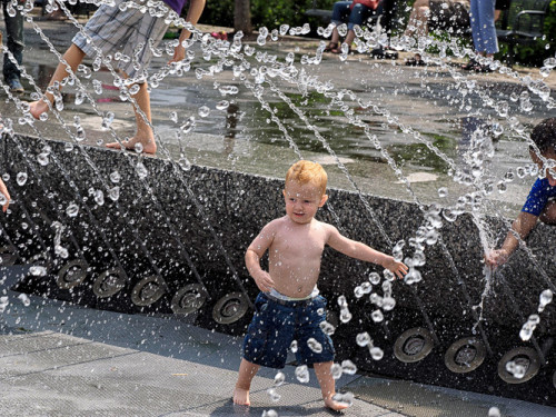 Kid uses a fountain as his personal water park.